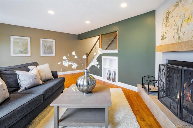 living room featuring recessed lighting, baseboards, wood finished floors, and a lit fireplace