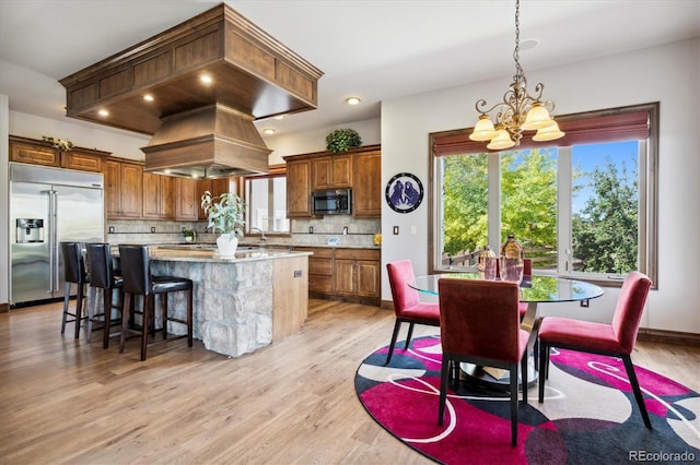 kitchen featuring light hardwood / wood-style flooring, decorative backsplash, a chandelier, and appliances with stainless steel finishes