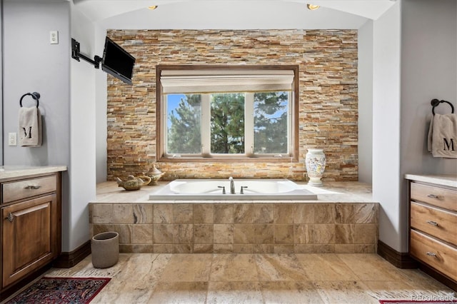 bathroom featuring vanity and a relaxing tiled tub