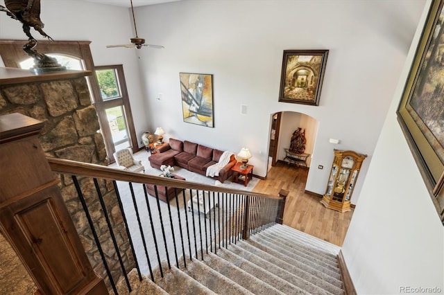 stairs with ceiling fan, hardwood / wood-style floors, and a high ceiling