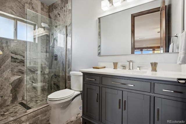 bathroom featuring vanity, a shower with shower door, and toilet