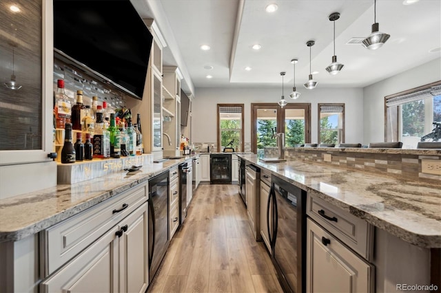 kitchen featuring beverage cooler, light hardwood / wood-style flooring, decorative light fixtures, light stone countertops, and a spacious island