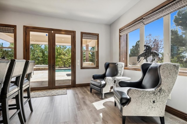 sitting room with light hardwood / wood-style floors, plenty of natural light, and french doors