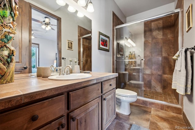 bathroom with vanity, toilet, ceiling fan, and a shower with door