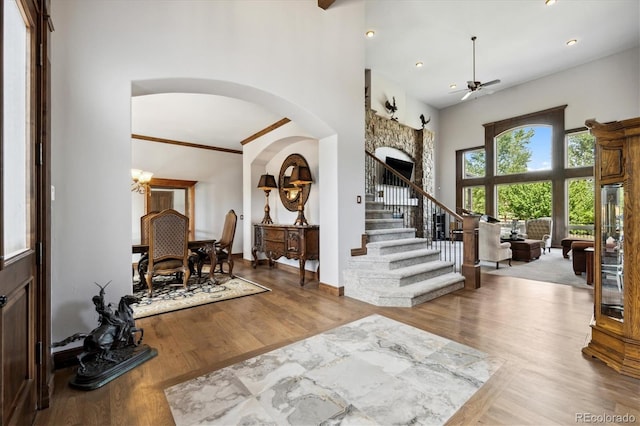 entrance foyer featuring ornamental molding, a towering ceiling, hardwood / wood-style floors, and ceiling fan