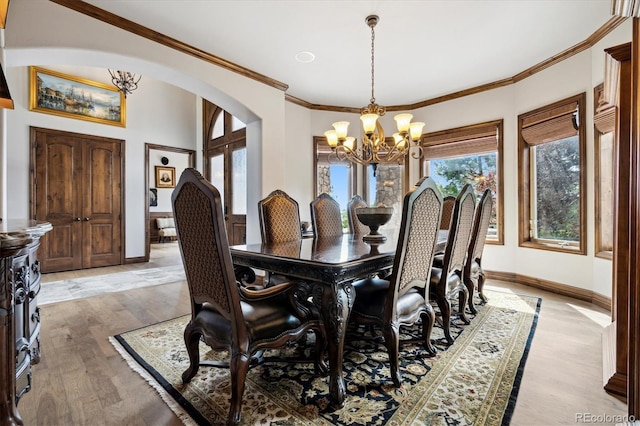 dining room with ornamental molding, light wood-type flooring, and a chandelier