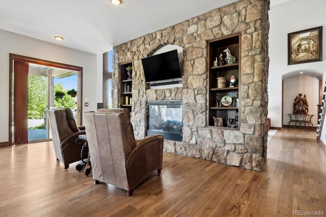 living room featuring a stone fireplace and hardwood / wood-style floors