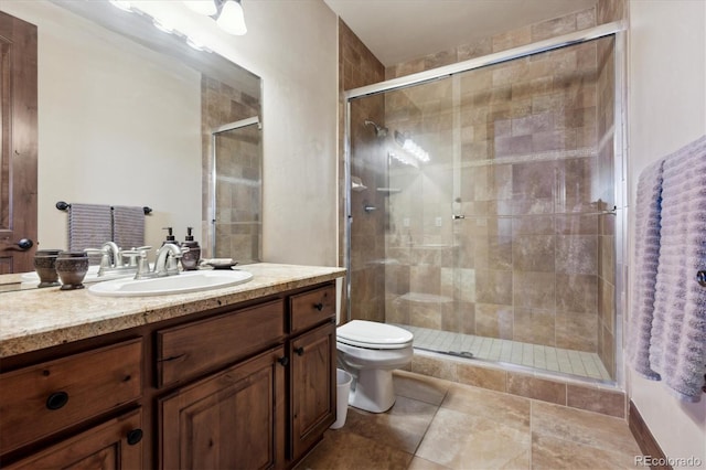 bathroom featuring tile patterned flooring, vanity, toilet, and a shower with door