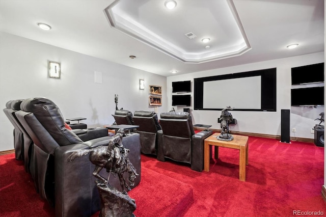 carpeted cinema room with a tray ceiling and built in features