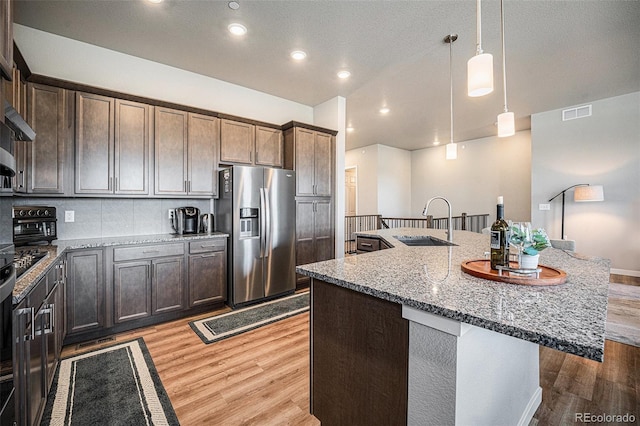 811 W 128th Pl, Westminster, CO 80234 - kitchen with stainless steel refrigerator with ice dispenser, wood finished floors, light stone counters, a kitchen island with sink, and decorative light fixtures