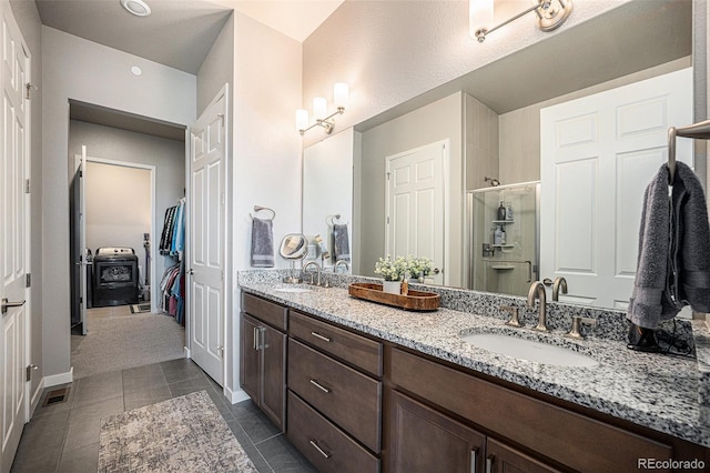 811 W 128th Pl, Westminster, CO 80234 - bathroom with double vanity, a stall shower, tile patterned floors, and a closet