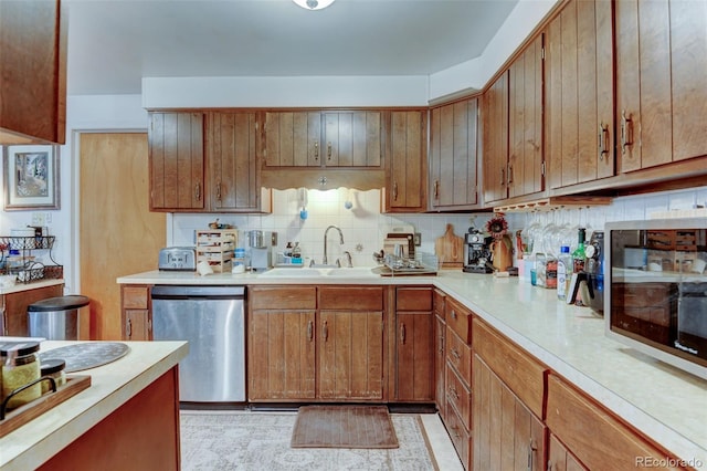 10560 W 63rd Ave, Arvada, CO 80004 - kitchen with stainless steel appliances, a sink, light countertops, brown cabinets, and backsplash