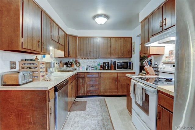 10560 W 63rd Ave, Arvada, CO 80004 - kitchen with stainless steel appliances, under cabinet range hood, backsplash, and light countertops