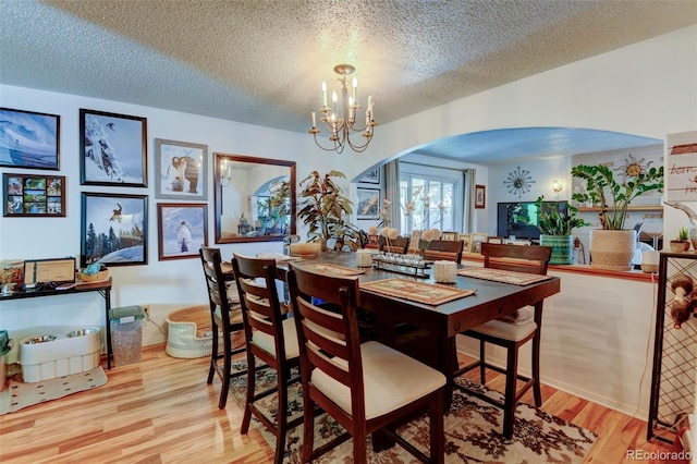 10560 W 63rd Ave, Arvada, CO 80004 - dining area with arched walkways, wood finished floors, a textured ceiling, and a chandelier