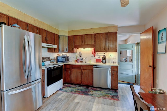 10560 W 63rd Ave, Arvada, CO 80004 - kitchen with stainless steel appliances, under cabinet range hood, a sink, light countertops, and light wood-type flooring
