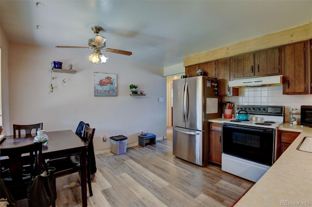 10560 W 63rd Ave, Arvada, CO 80004 - kitchen featuring freestanding refrigerator, range with electric stovetop, under cabinet range hood, light countertops, and backsplash