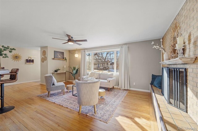 living room with a large fireplace, ceiling fan, and light hardwood / wood-style flooring