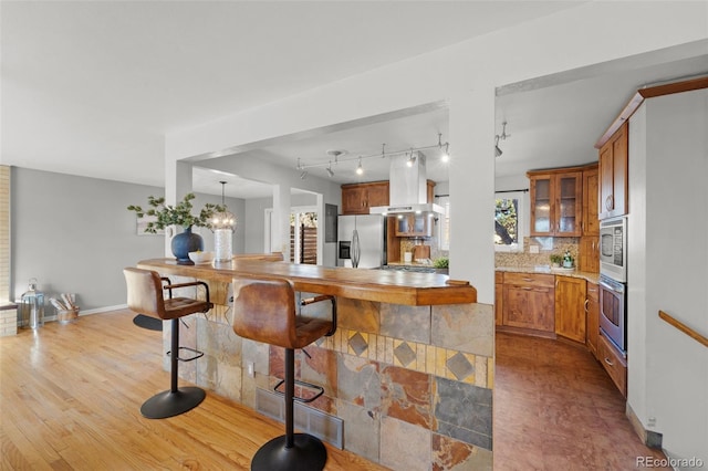 kitchen with an inviting chandelier, light hardwood / wood-style floors, decorative light fixtures, decorative backsplash, and appliances with stainless steel finishes