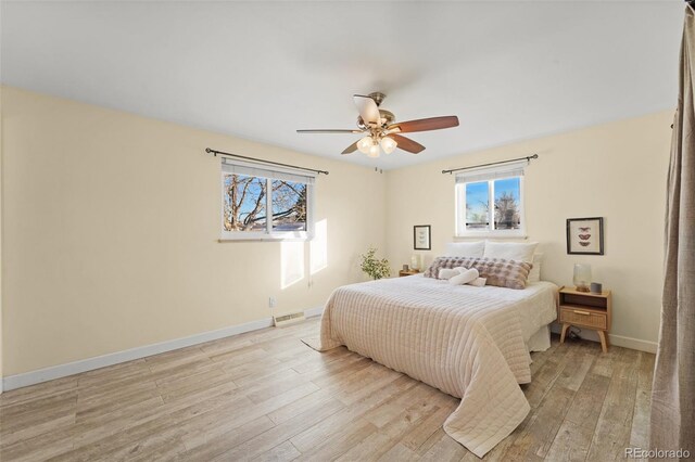 bedroom with ceiling fan, light wood-type flooring, and multiple windows