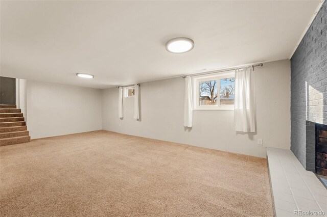 basement with a fireplace and light colored carpet