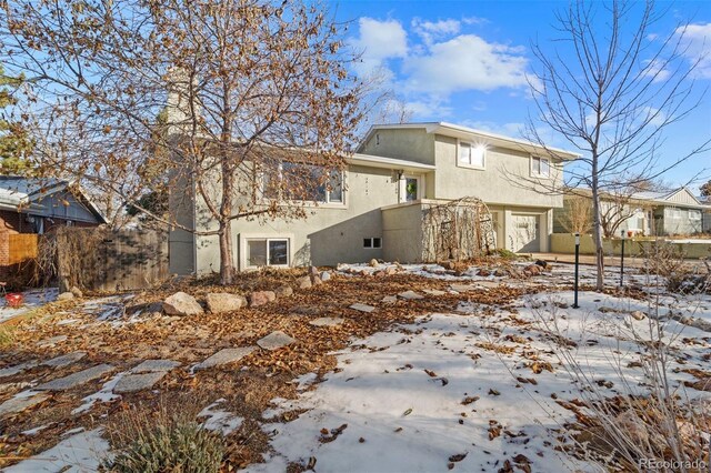 snow covered back of property with a garage