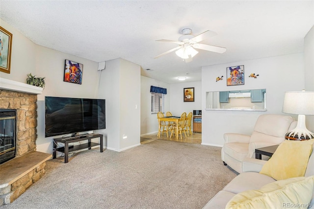 carpeted living room featuring ceiling fan and a fireplace