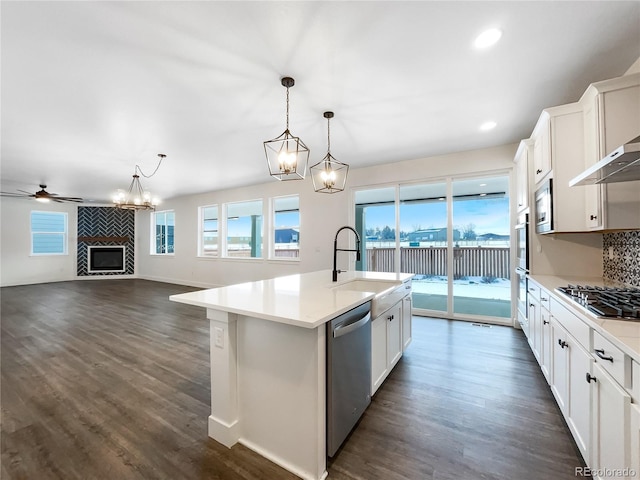 kitchen featuring stainless steel appliances, a sink, light countertops, a center island with sink, and pendant lighting