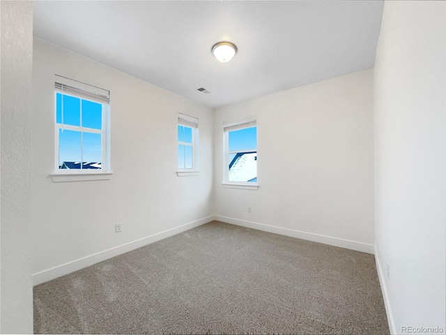 spare room featuring carpet, visible vents, and baseboards