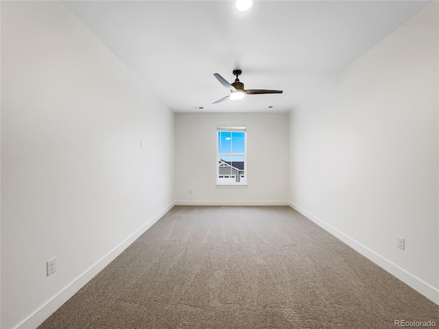 carpeted spare room with ceiling fan and baseboards