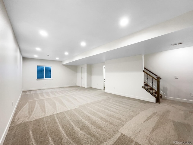 finished below grade area featuring recessed lighting, light colored carpet, visible vents, and stairs