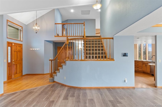 foyer featuring a notable chandelier, stairs, wood finished floors, and visible vents