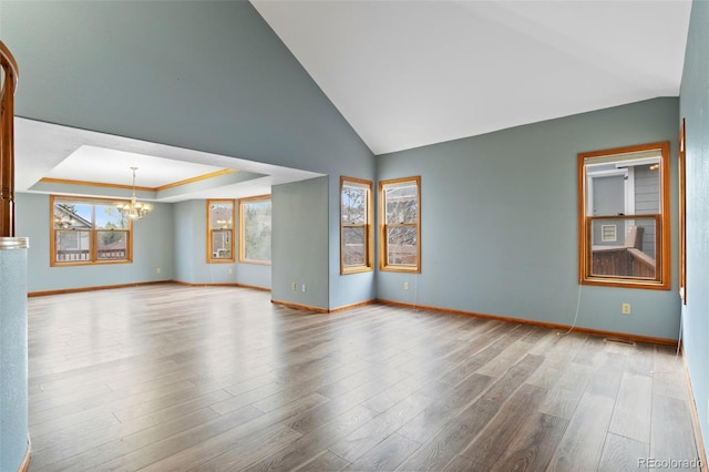 empty room with baseboards, lofted ceiling, wood finished floors, and a chandelier