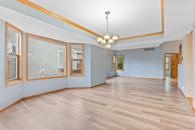 spare room featuring a chandelier, a tray ceiling, visible vents, and light wood-type flooring