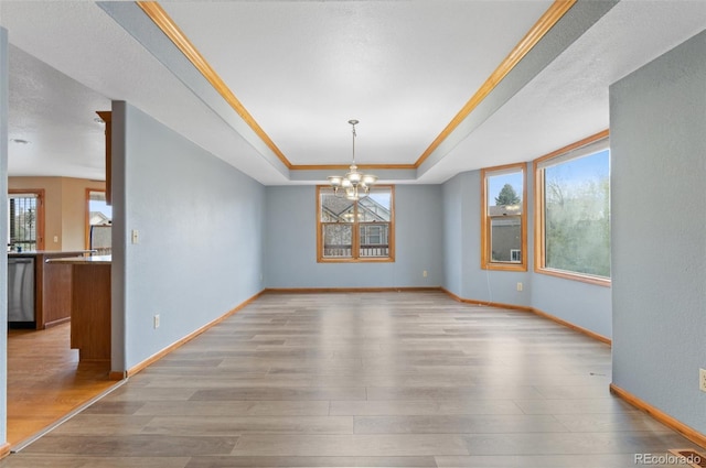 unfurnished dining area with baseboards, light wood-style flooring, a notable chandelier, and a tray ceiling