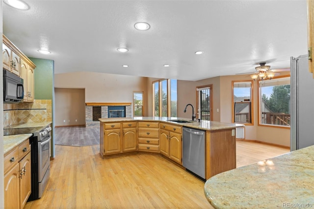 kitchen with light wood-type flooring, a sink, open floor plan, and stainless steel appliances
