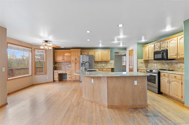 kitchen featuring light wood finished floors, backsplash, a center island with sink, and stainless steel appliances