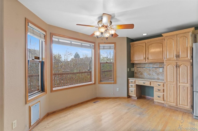 interior space with ceiling fan, plenty of natural light, built in study area, and light wood-style floors