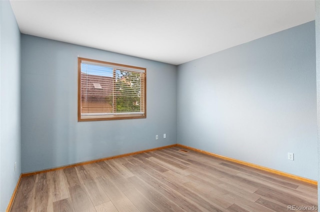 spare room with baseboards and wood finished floors