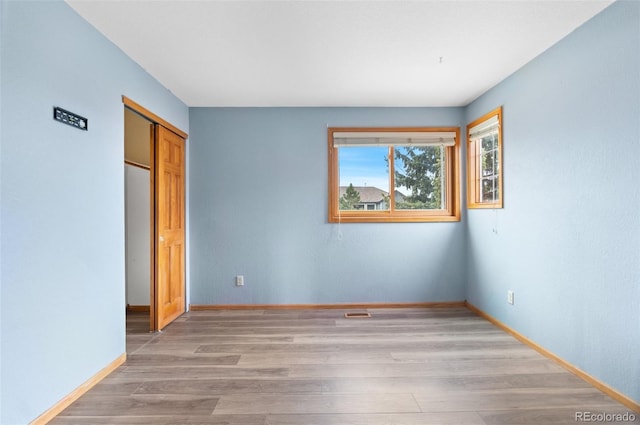 unfurnished bedroom featuring a closet, baseboards, and light wood-style floors
