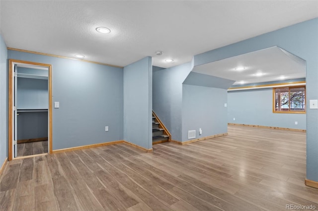 below grade area featuring visible vents, wood finished floors, baseboards, stairway, and recessed lighting