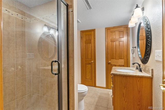 bathroom featuring a textured ceiling, tile patterned flooring, a stall shower, vanity, and toilet