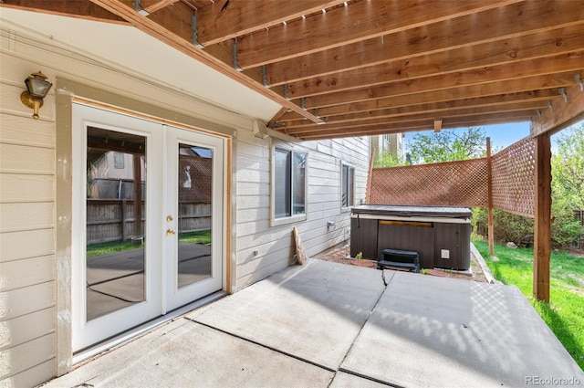 view of patio / terrace featuring a hot tub, fence, and french doors