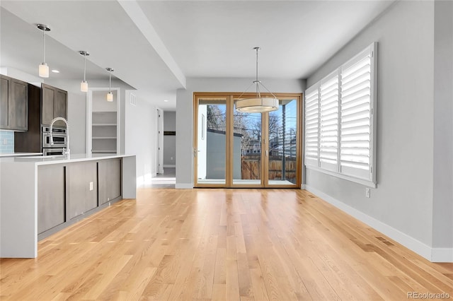 interior space featuring dark brown cabinets, light wood-type flooring, and hanging light fixtures