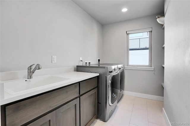 laundry room with cabinets, light tile patterned floors, sink, and washing machine and clothes dryer