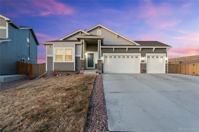 craftsman inspired home with a garage, concrete driveway, fence, and stone siding