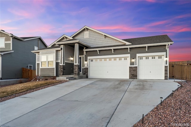 craftsman inspired home with an attached garage, stone siding, driveway, and fence