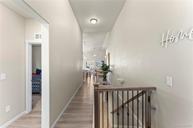 corridor featuring visible vents, vaulted ceiling, wood finished floors, and an upstairs landing