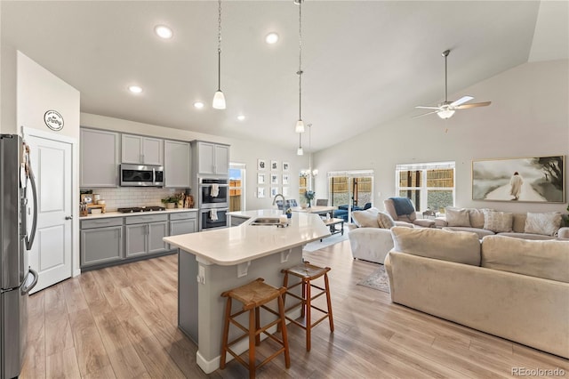 kitchen with appliances with stainless steel finishes, light wood-type flooring, gray cabinets, and open floor plan