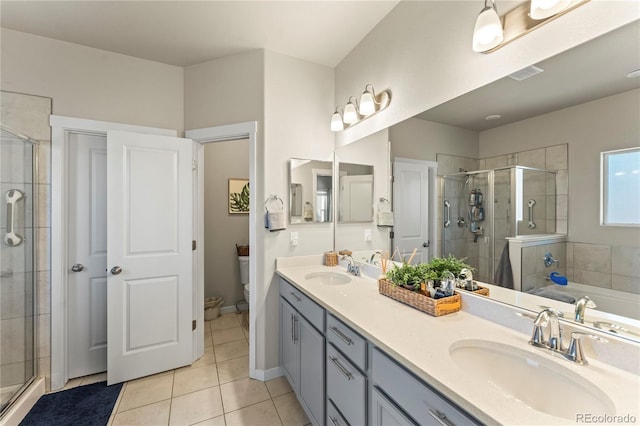 bathroom featuring toilet, a stall shower, tile patterned flooring, and a sink