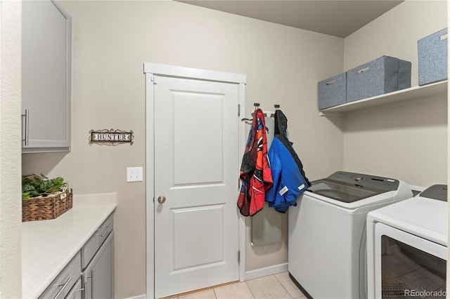 washroom with light tile patterned floors, washing machine and dryer, baseboards, and cabinet space